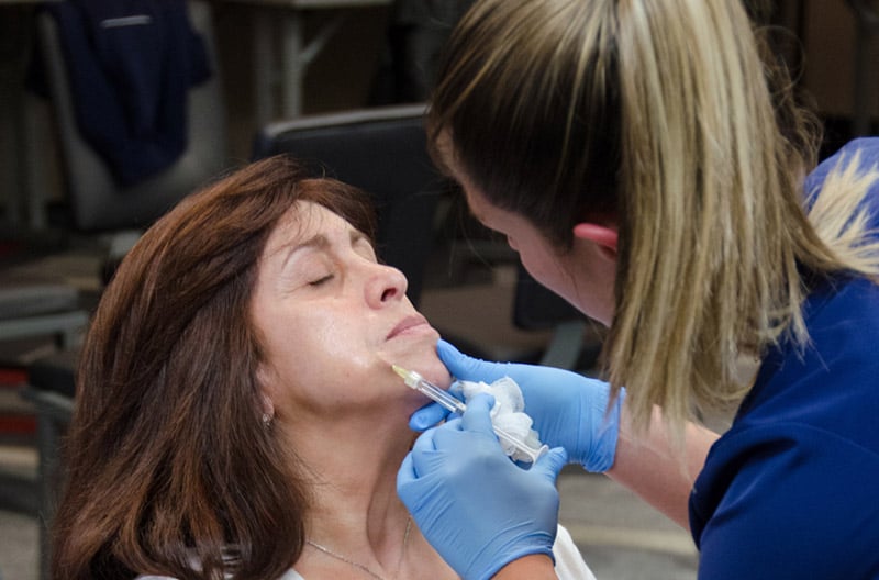 Doctor performing aesthetic injection on woman face