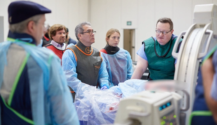 Physician stands in front of cadaver specimen and teaches students pain management