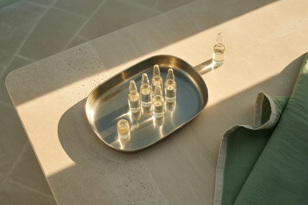 A stainless steel tray of sealed glass ampoules in raking light