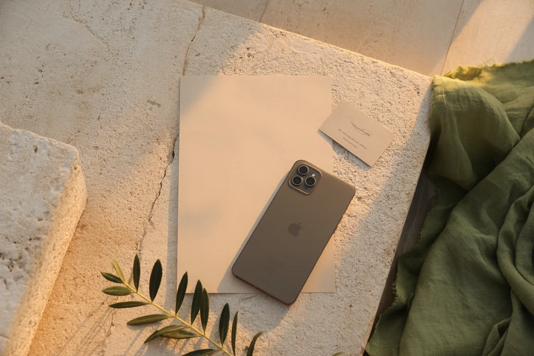A blank sheet of paper and a phone face down on limestone in raking light