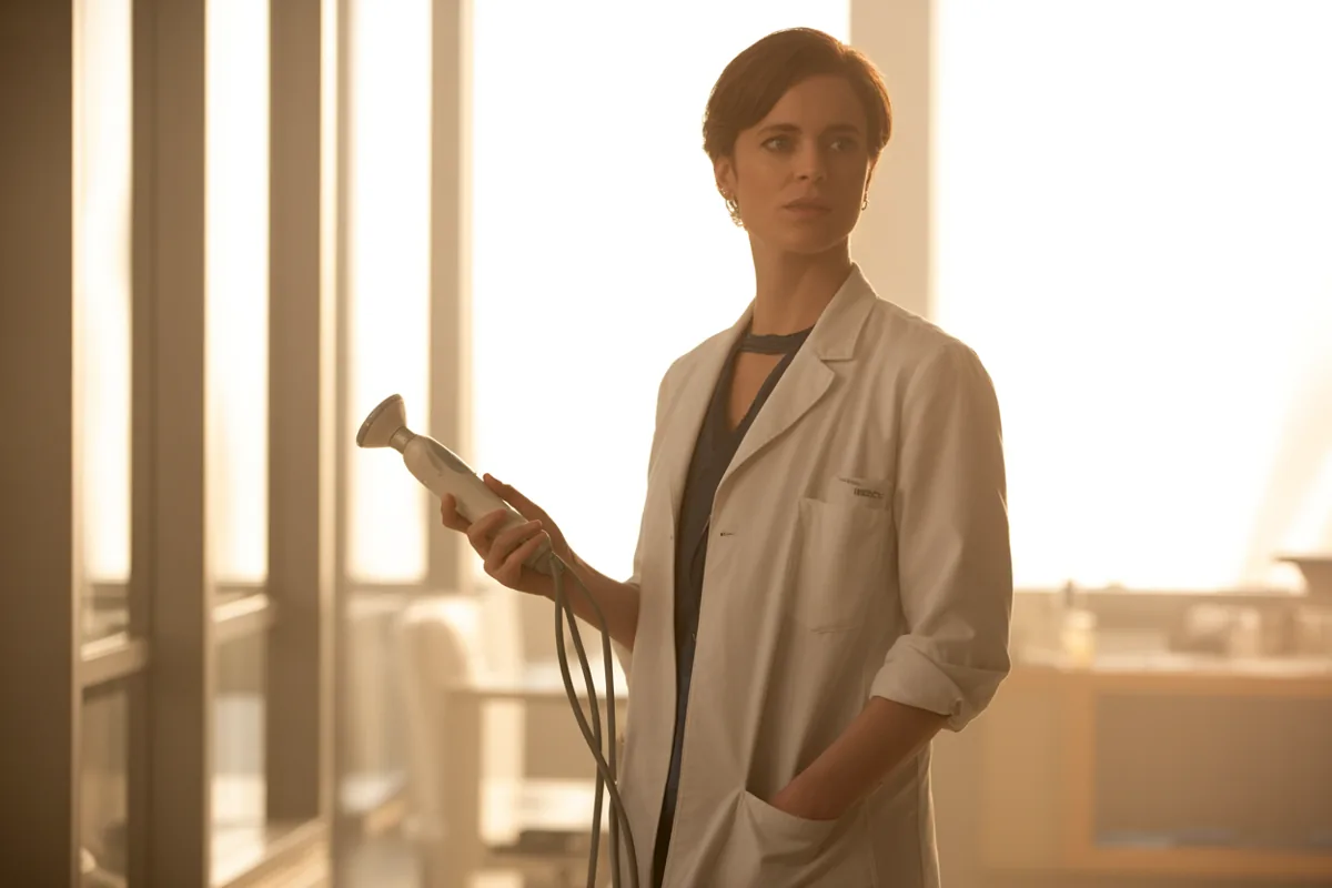 Physician holding a portable ultrasound probe in a sunlit clinic corridor at golden hour
