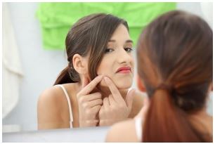 woman with acne in mirror